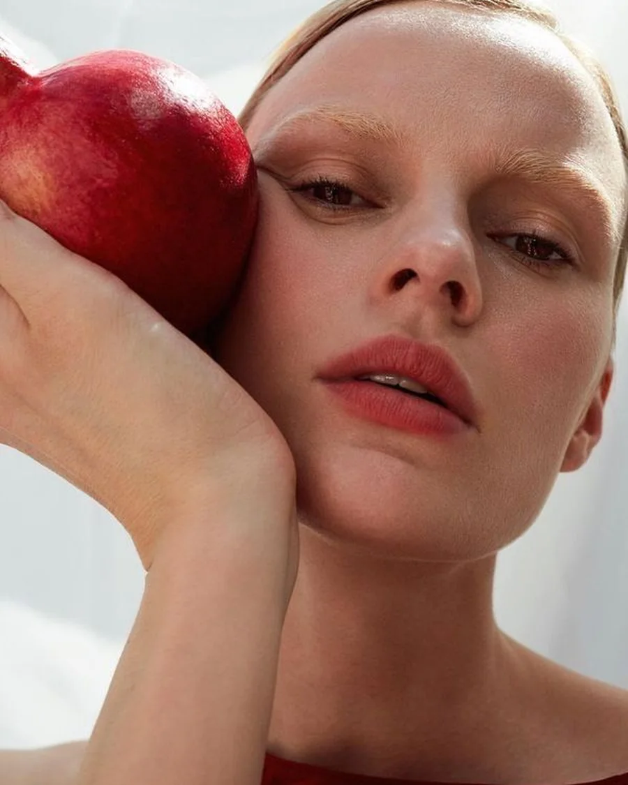 Woman holding a pomegranate against her cheek