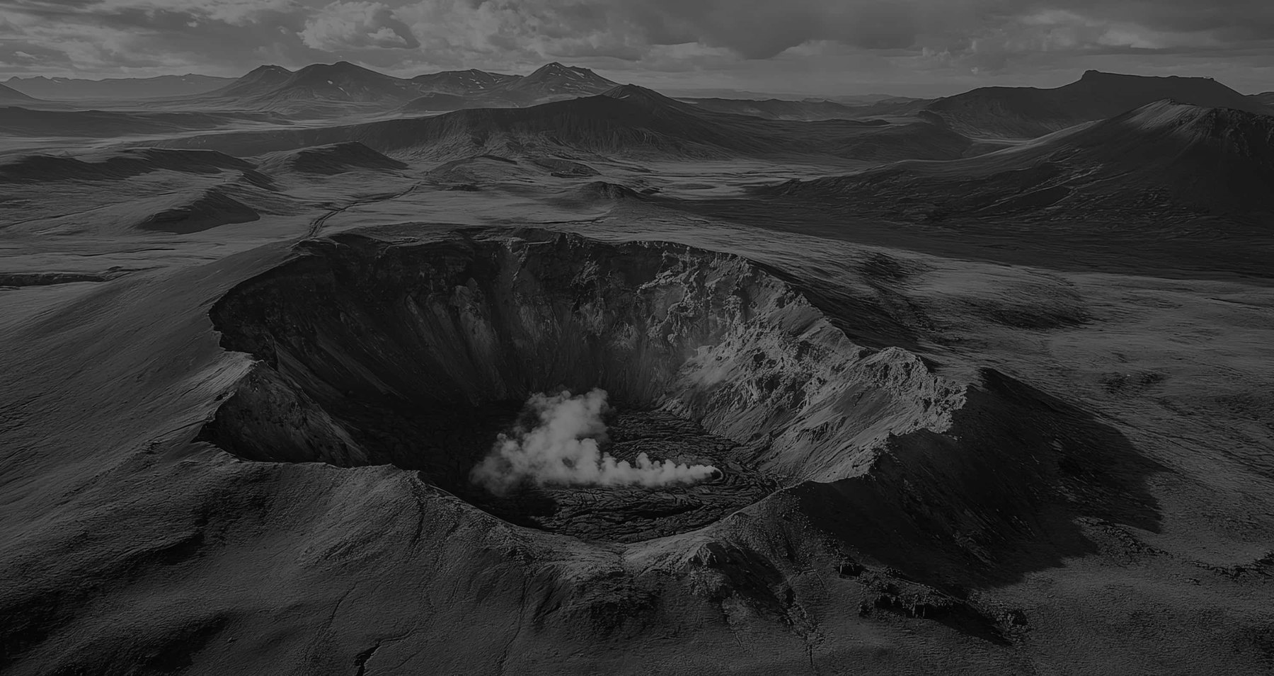 Monochrome view of a volcanic basin under cloudy skies.
