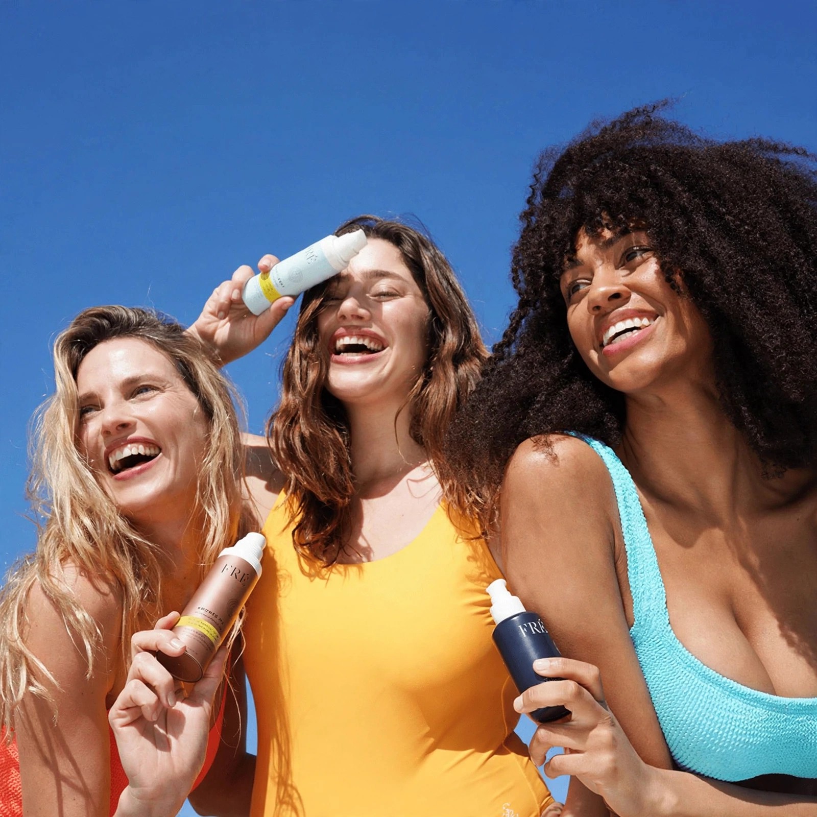 Smiling group outdoors showing three Fre skincare products.