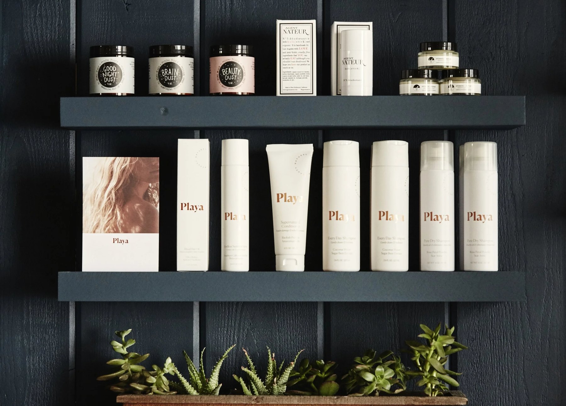 Playa haircare range displayed on dark wall shelves.